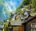 Charming wooden houses on a lush mountainside in Hallstatt, Austria under bright daylight.
