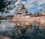 Reflection of Matsumoto Castle in Japan during autumn, surrounded by a serene lake.