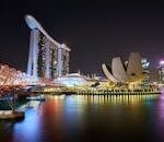 Stunning night view of Marina Bay Sands and Helix Bridge illuminated over water in Singapore.