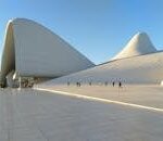 Striking modern architecture of the Heydar Aliyev Center in Baku with people walking under clear skies.