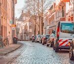 Picturesque street scene in Groningen with parked bicycles and cars lining cobblestone road.