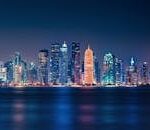 Captivating night view of Doha's illuminated skyline reflecting over the water.
