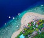 A stunning aerial view of Oslob Beach, Cebu, with vibrant blue waters and lush greenery.