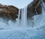 A breathtaking view of a towering waterfall amidst icy landscapes in Iceland.