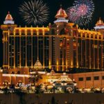 Colorful firework over famous modern palace with illuminated facade and square located in Macau at night