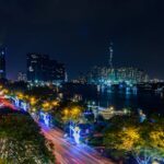 Stunning nighttime view of Ho Chi Minh City's skyline with illuminated roads and skyscrapers by the Saigon River.